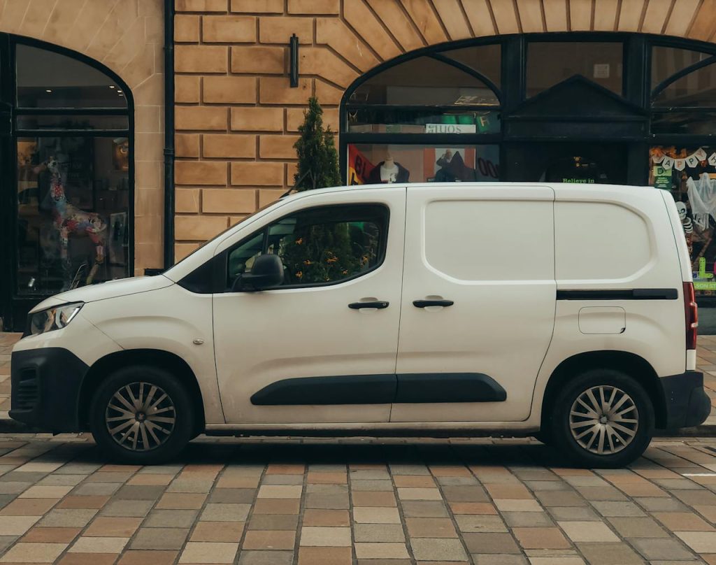Side view of a white van parked on a city street, ideal for urban transport themes.